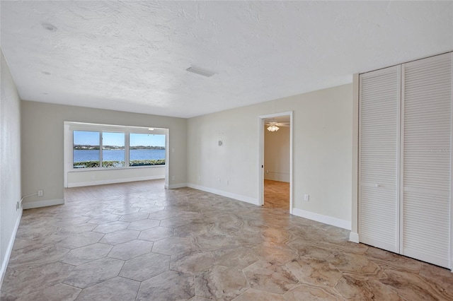 interior space featuring a water view, baseboards, and a textured ceiling