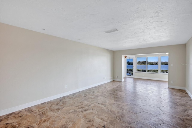 spare room with visible vents, a textured ceiling, and baseboards