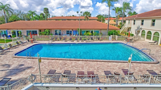 community pool with a patio and fence