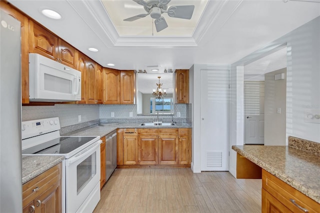 kitchen featuring visible vents, brown cabinetry, a raised ceiling, appliances with stainless steel finishes, and a sink