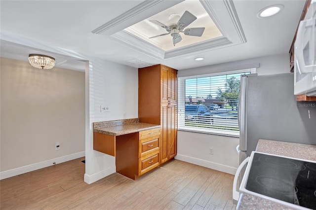 kitchen with brown cabinetry, a raised ceiling, white appliances, and light wood-style flooring