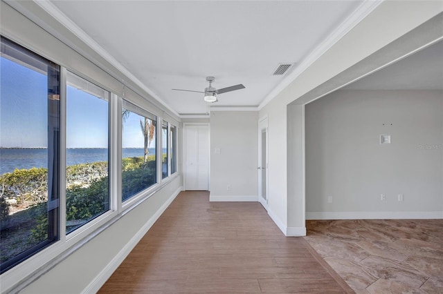 unfurnished sunroom featuring a water view, visible vents, and a ceiling fan