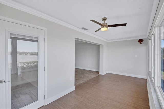 unfurnished room with light wood finished floors, visible vents, ornamental molding, and baseboards