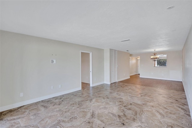 unfurnished room featuring a chandelier and baseboards