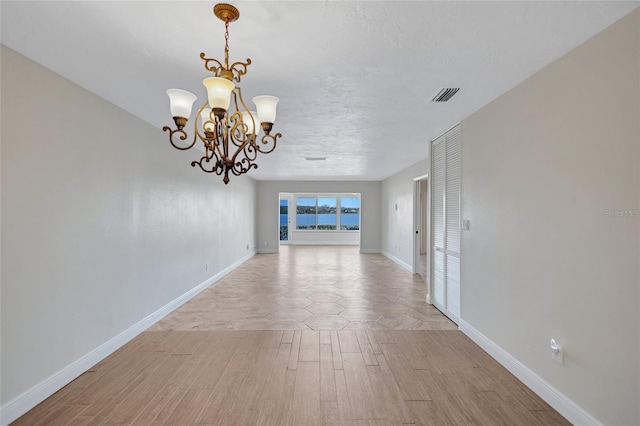 interior space with a notable chandelier, light wood finished floors, visible vents, and baseboards