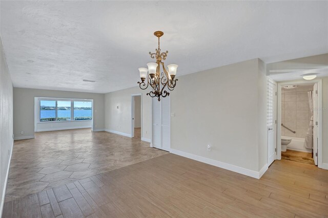 interior space featuring light wood-style floors, a notable chandelier, and baseboards