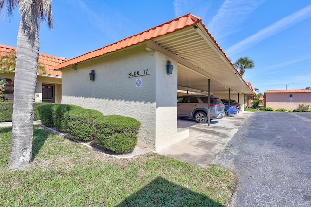 view of property exterior featuring covered parking, a tiled roof, and stucco siding