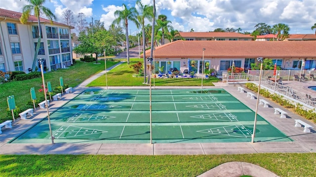 view of property's community featuring shuffleboard and a yard