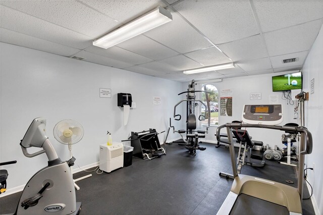 workout area featuring a drop ceiling, visible vents, and baseboards