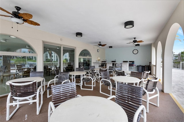 view of patio featuring exterior kitchen, outdoor dining area, and a ceiling fan