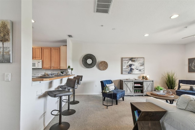 living area featuring recessed lighting, visible vents, and light colored carpet