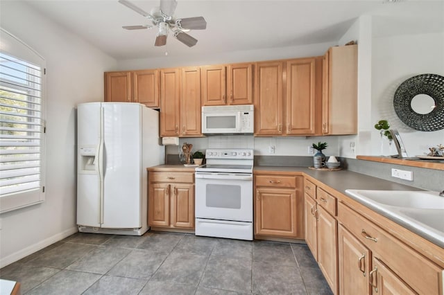 kitchen featuring a ceiling fan, a sink, white appliances, dark tile patterned floors, and baseboards