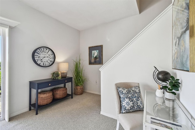 living area with baseboards and light colored carpet