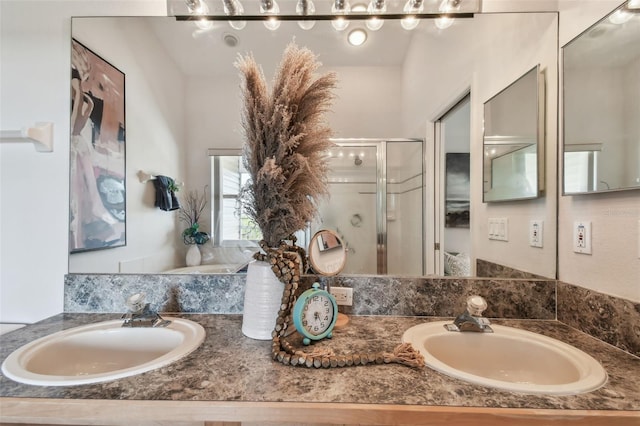 bathroom with a sink, a shower stall, and double vanity