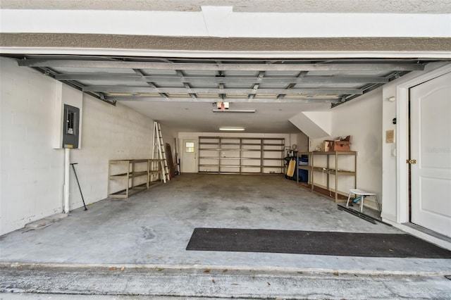 garage featuring concrete block wall, electric panel, and a garage door opener