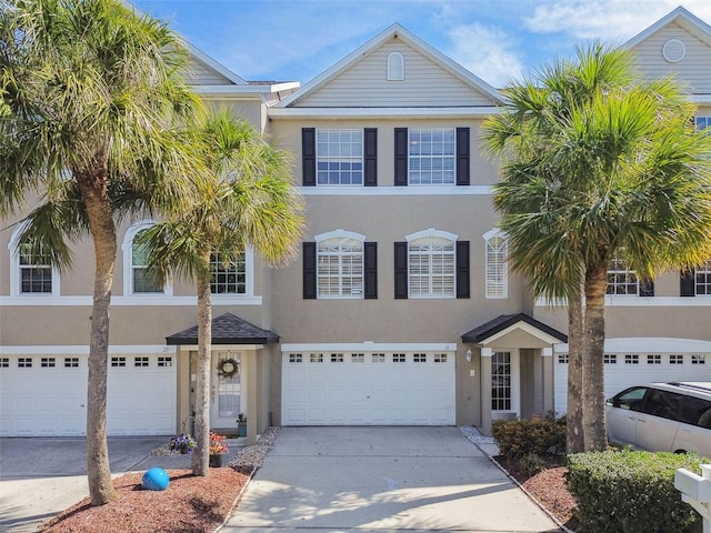 multi unit property with driveway, an attached garage, and stucco siding