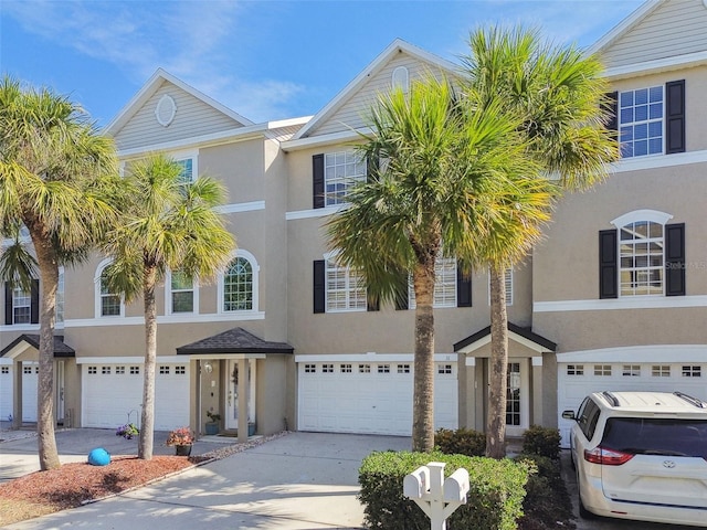 multi unit property with a garage, concrete driveway, and stucco siding