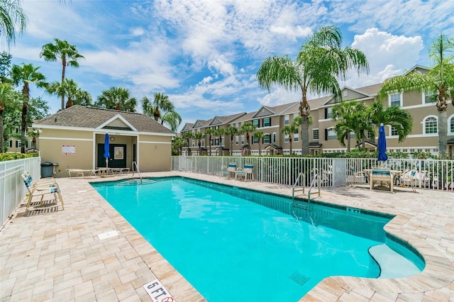 pool with a residential view, fence, and a patio