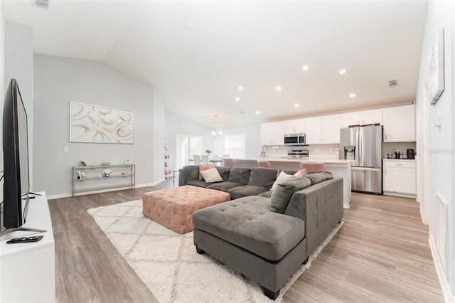 living area with light wood-type flooring, lofted ceiling, a chandelier, and recessed lighting