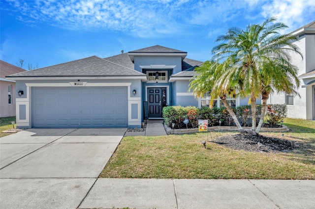 view of front of property featuring a garage, a front yard, concrete driveway, and stucco siding