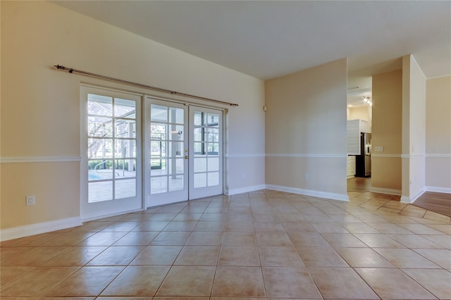 unfurnished room featuring light tile patterned floors, baseboards, and french doors