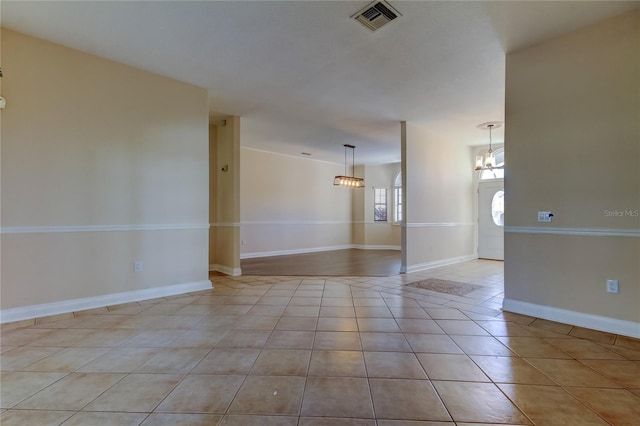 tiled empty room featuring baseboards, visible vents, and an inviting chandelier