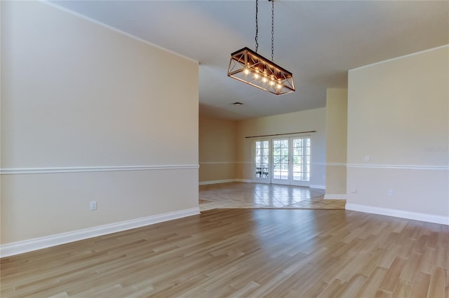 unfurnished room with baseboards, french doors, an inviting chandelier, and light wood-style floors