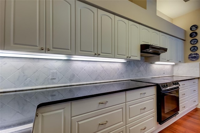 kitchen with tasteful backsplash, dark countertops, light wood-type flooring, under cabinet range hood, and black / electric stove