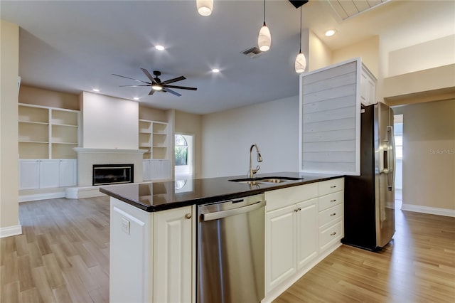 kitchen with appliances with stainless steel finishes, dark countertops, a sink, and visible vents