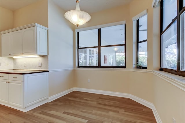unfurnished dining area featuring light wood-type flooring and baseboards