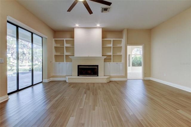 unfurnished living room with a wealth of natural light, a fireplace, and light wood-style flooring