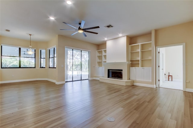 unfurnished living room with recessed lighting, visible vents, baseboards, light wood-style floors, and a glass covered fireplace