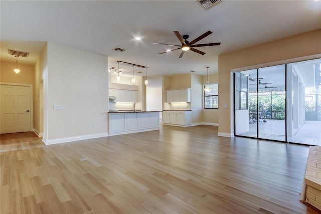 unfurnished living room featuring light wood finished floors, visible vents, and a ceiling fan