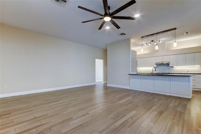 kitchen featuring dark countertops, decorative backsplash, visible vents, and under cabinet range hood