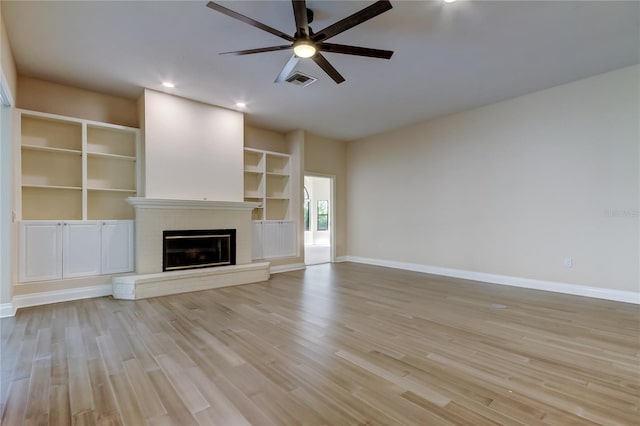 unfurnished living room featuring ceiling fan, visible vents, baseboards, light wood-style floors, and a brick fireplace