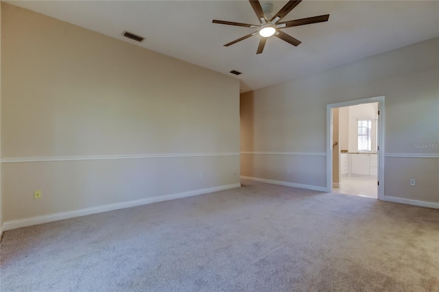 spare room with vaulted ceiling, carpet flooring, visible vents, and a ceiling fan