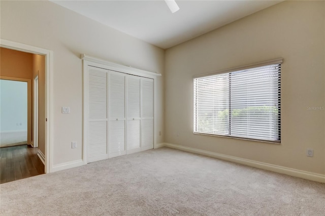 unfurnished bedroom with a ceiling fan, carpet, a closet, and baseboards