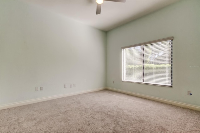 empty room with carpet floors, a ceiling fan, and baseboards