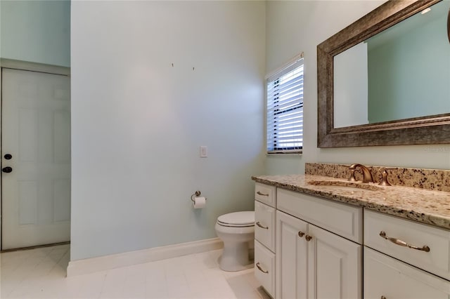 bathroom with toilet, baseboards, and vanity