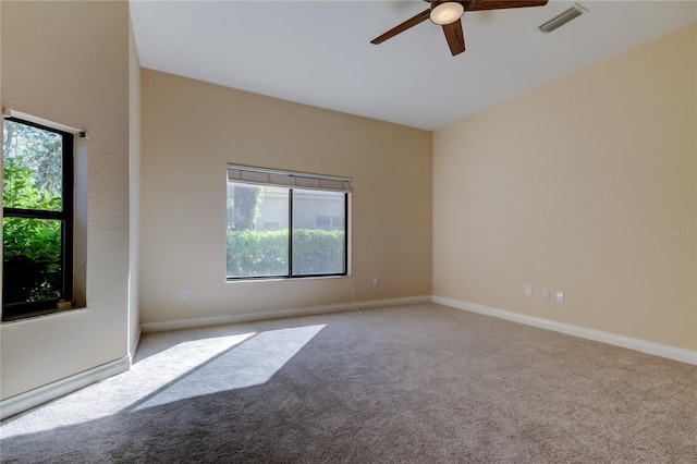 empty room with carpet floors, a ceiling fan, visible vents, and baseboards