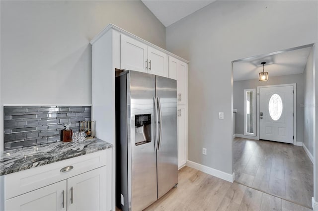 kitchen featuring light wood finished floors, stone countertops, white cabinetry, stainless steel refrigerator with ice dispenser, and backsplash