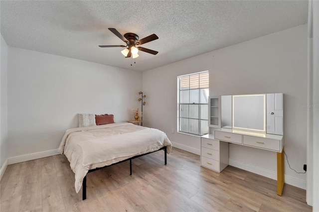 bedroom featuring baseboards, a textured ceiling, a ceiling fan, and light wood-style floors