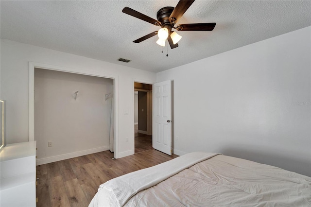 bedroom with a ceiling fan, a textured ceiling, baseboards, and wood finished floors