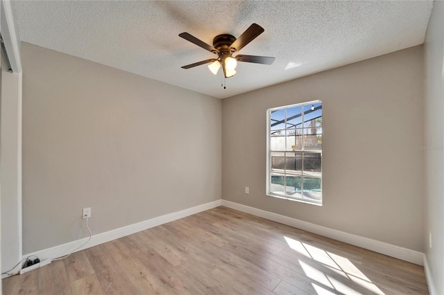 spare room with light wood-style flooring, baseboards, ceiling fan, and a textured ceiling