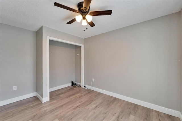 interior space with ceiling fan, light wood-style flooring, baseboards, and a textured ceiling