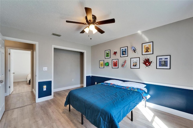 bedroom with a textured ceiling, light wood-style flooring, visible vents, and baseboards