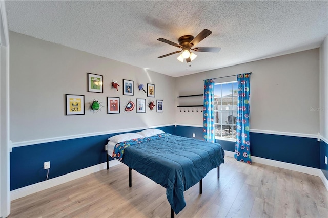 bedroom with a textured ceiling, ceiling fan, light wood-style flooring, and baseboards