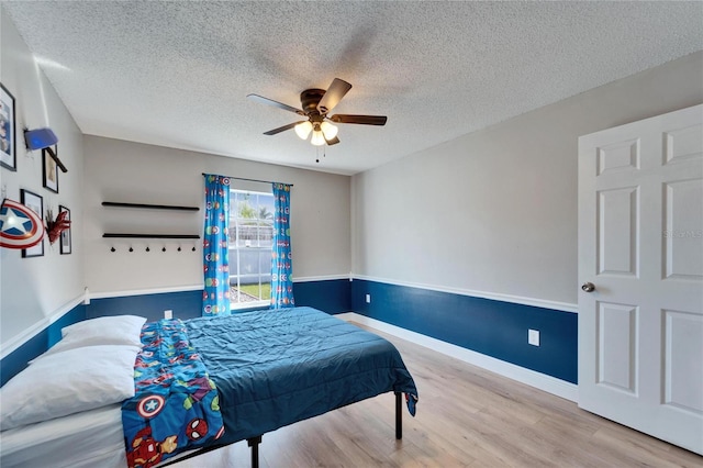 bedroom with a textured ceiling, ceiling fan, wood finished floors, and baseboards