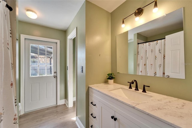 full bathroom featuring wood finished floors, vanity, and baseboards