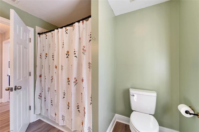 full bath with visible vents, a shower with shower curtain, toilet, wood finished floors, and baseboards